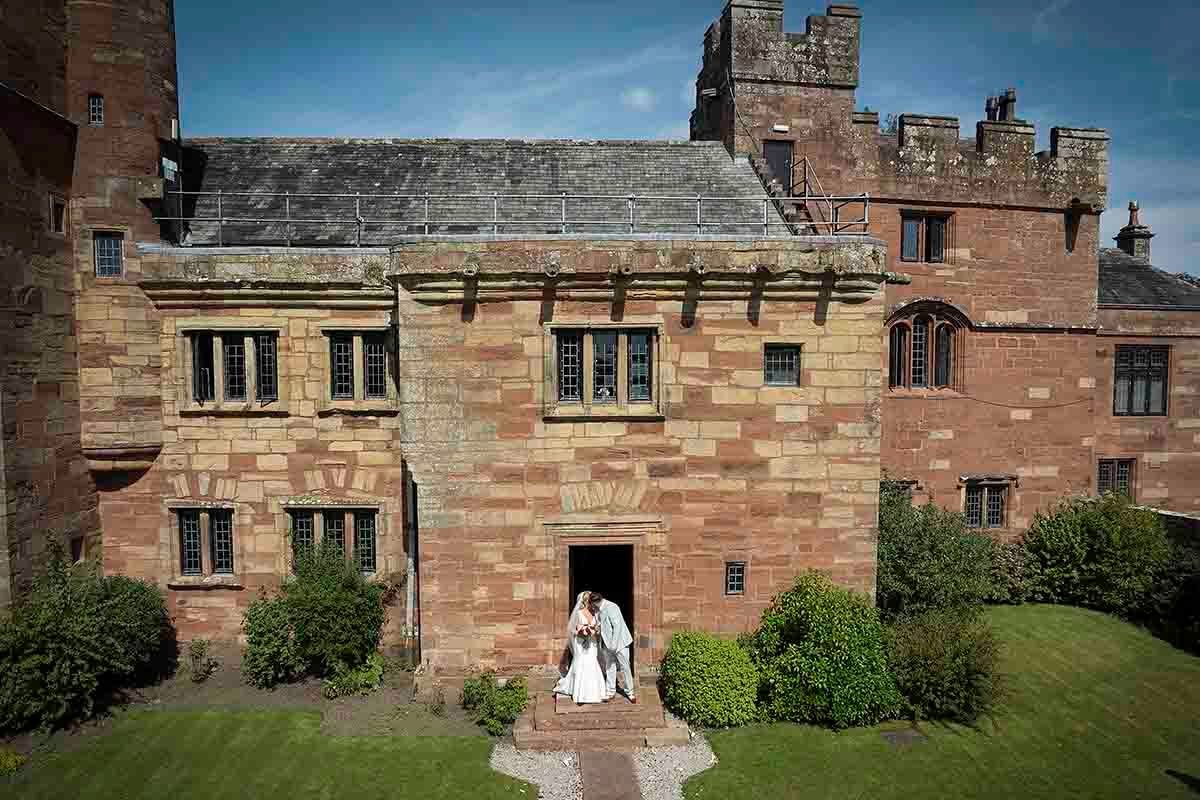 Bride and Groom share a kiss on the steps of Dalston Hall - Cumbria's premier wedding venue