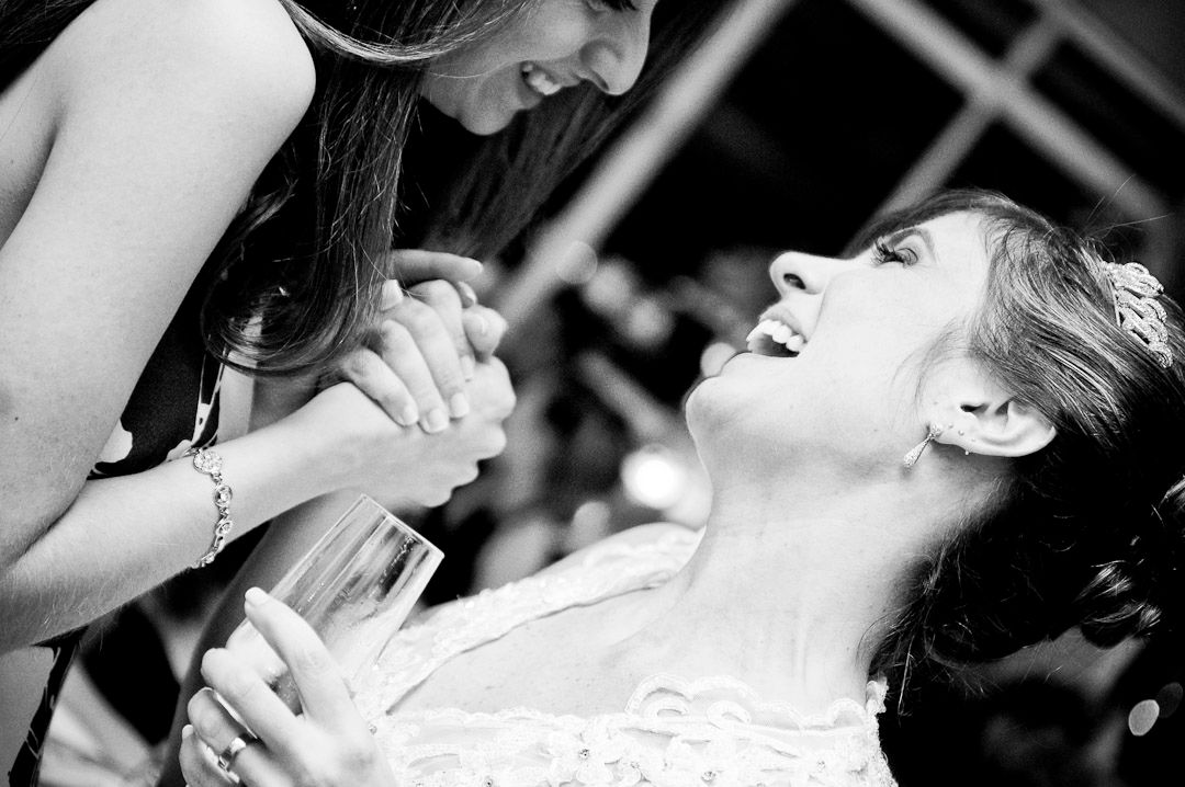 Black and white photo of a smiling bride and groom embracing, showcasing her wedding ring during their first dance.