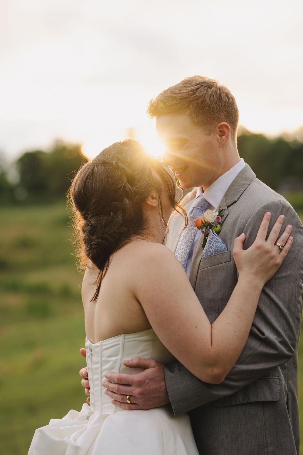 Bride and groom sharing an intimate moment bathed in golden sunset light at outdoor wedding.