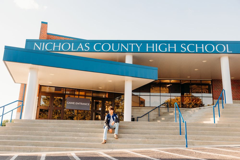 Student walking down steps outside Nicholas County High School entrance on a sunny day.