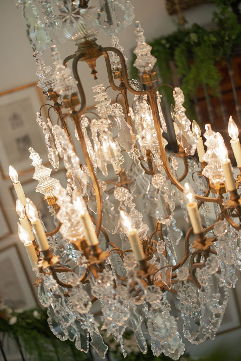Elegant antique brass chandelier with crystal drops and lit candle lights in a luxurious interior setting.
