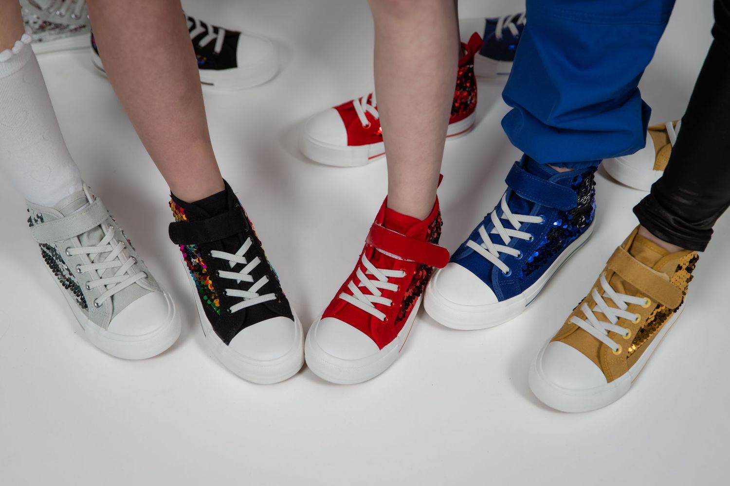 Colorful high-top sneakers in white, black, red, blue, and gold displayed on feet against a white background.