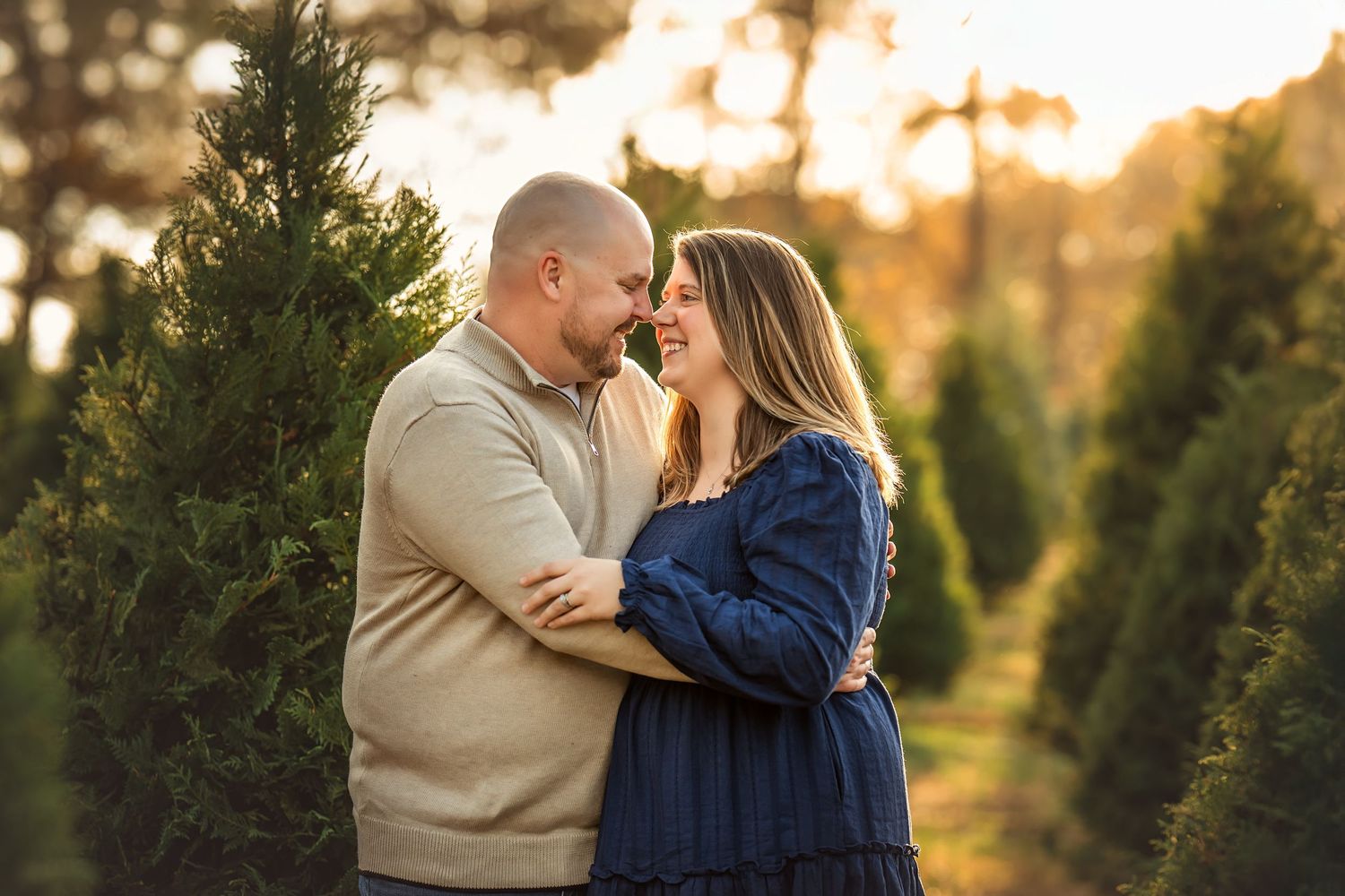 Family laughing together at a Christmas tree farm during golden hour sunset.