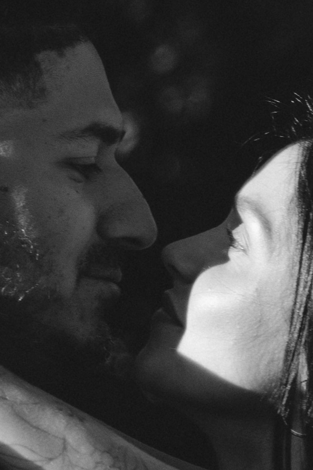 Romantic black and white close-up portrait of a couple facing each other about to kiss.