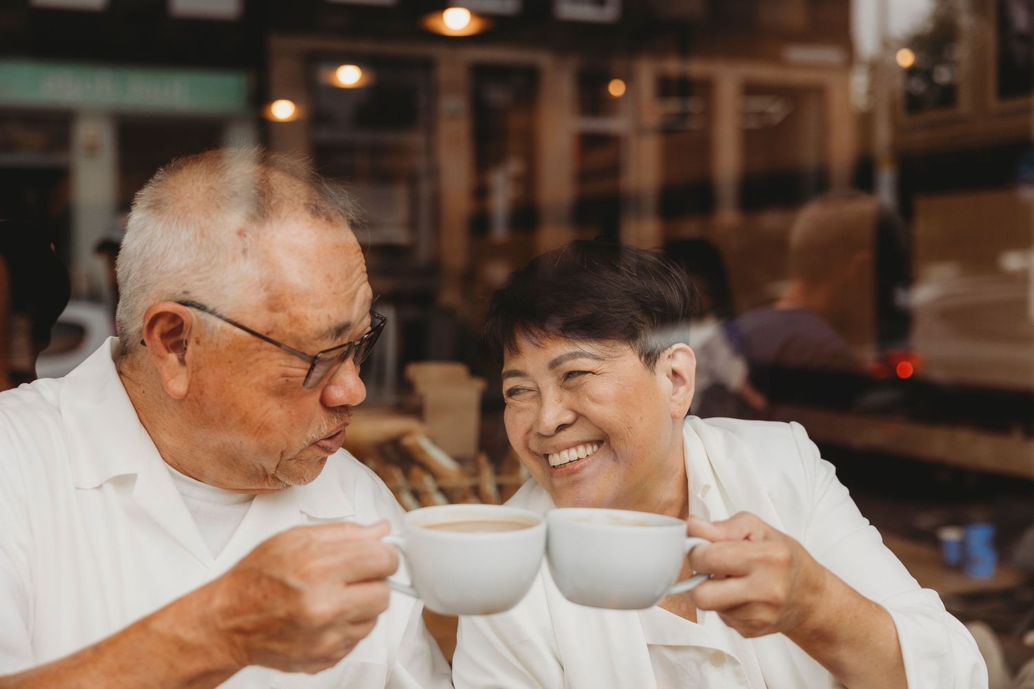Couple sharing an intimate moment over coffee cups and ultrasound photos at a cafe table.