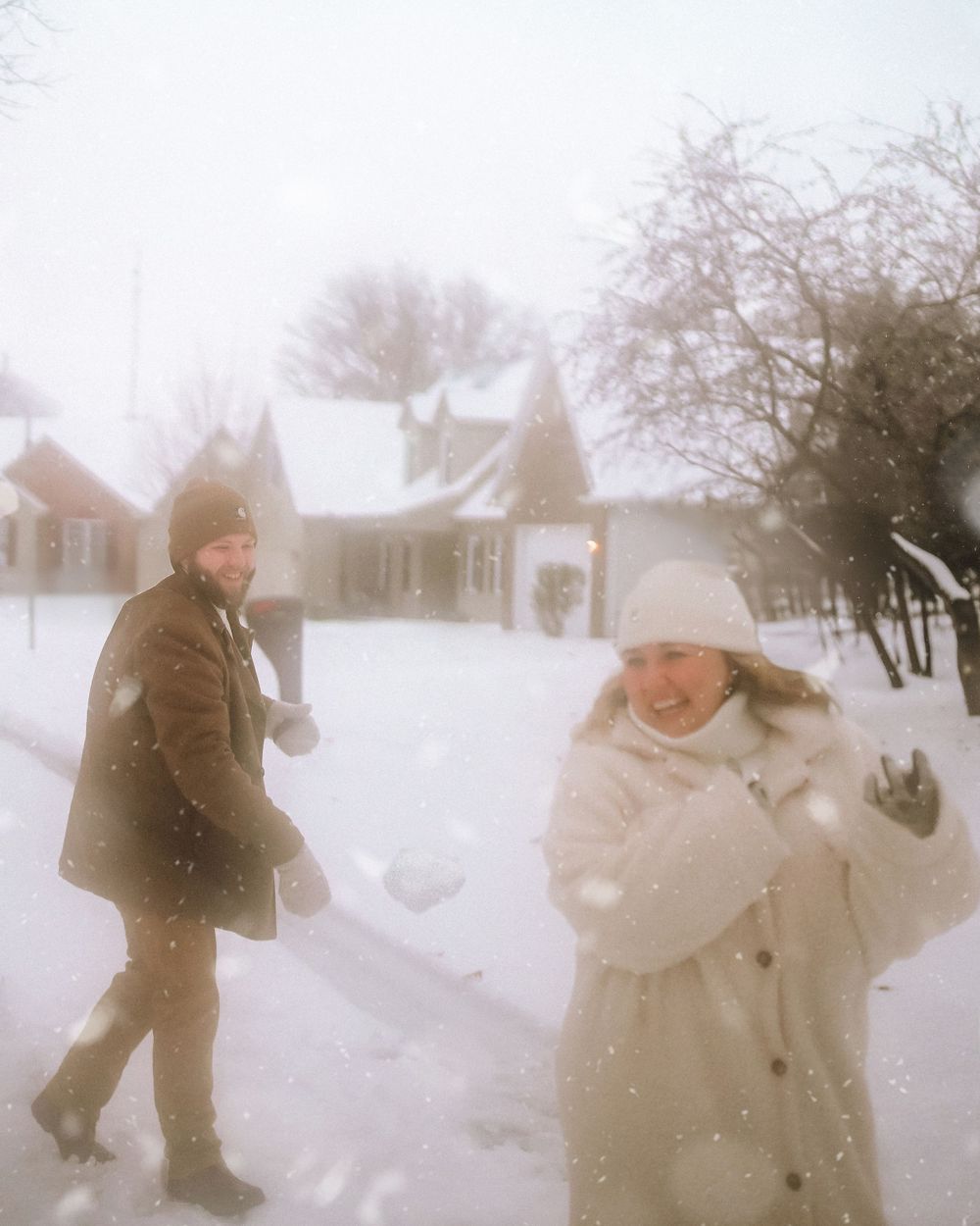 Playful winter scene with people enjoying snowfall in cozy winter attire.
