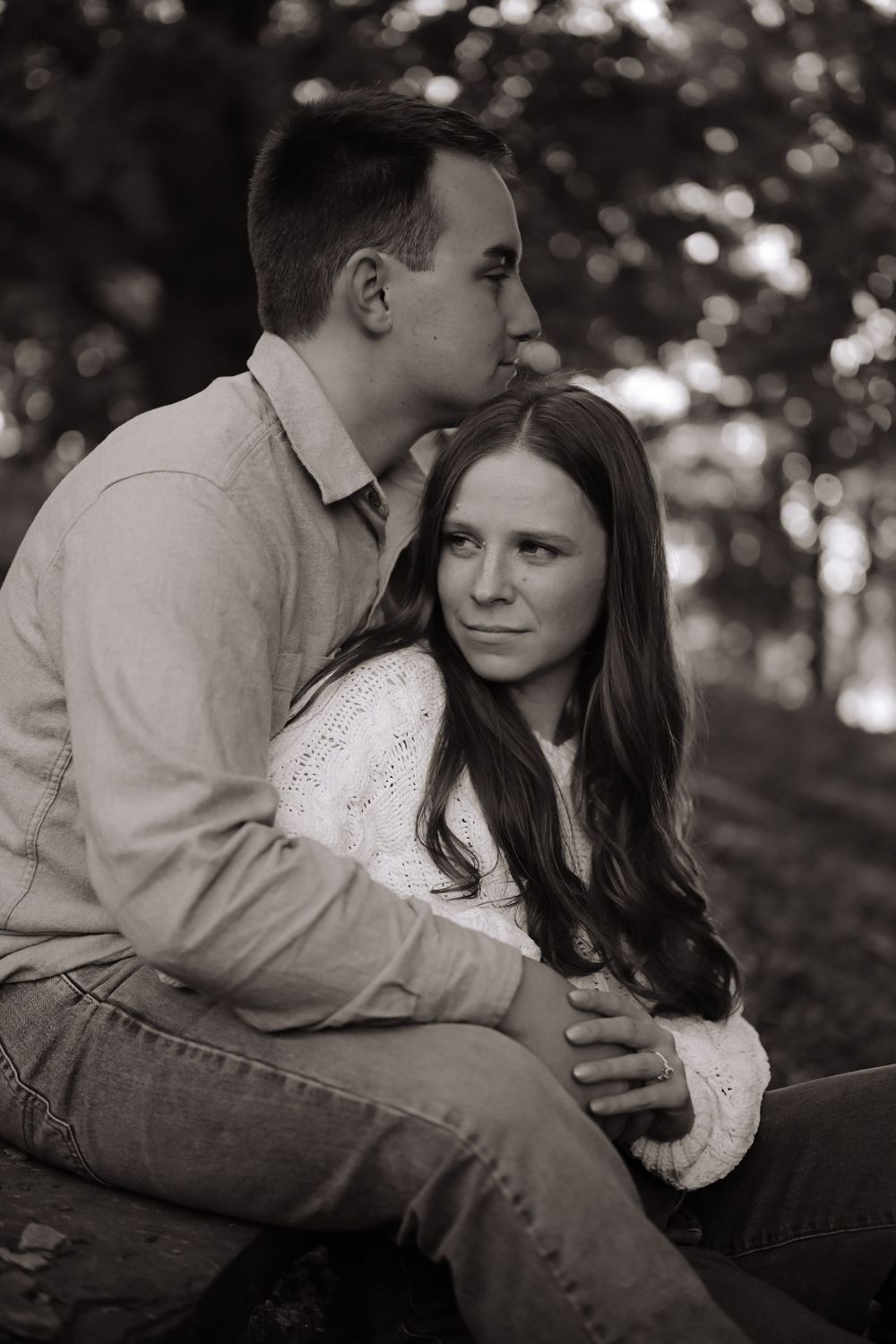 Black and white intimate portrait of couple sitting outdoors.