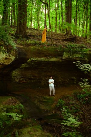 Wide panoramic view of a forest trail with exposed rock ledge walls showcasing the natural layered geology.