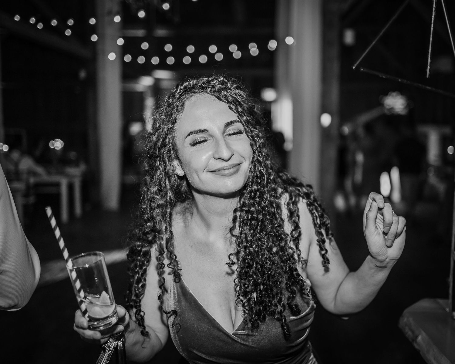 A dimly lit venue with string lights creates an intimate party atmosphere.