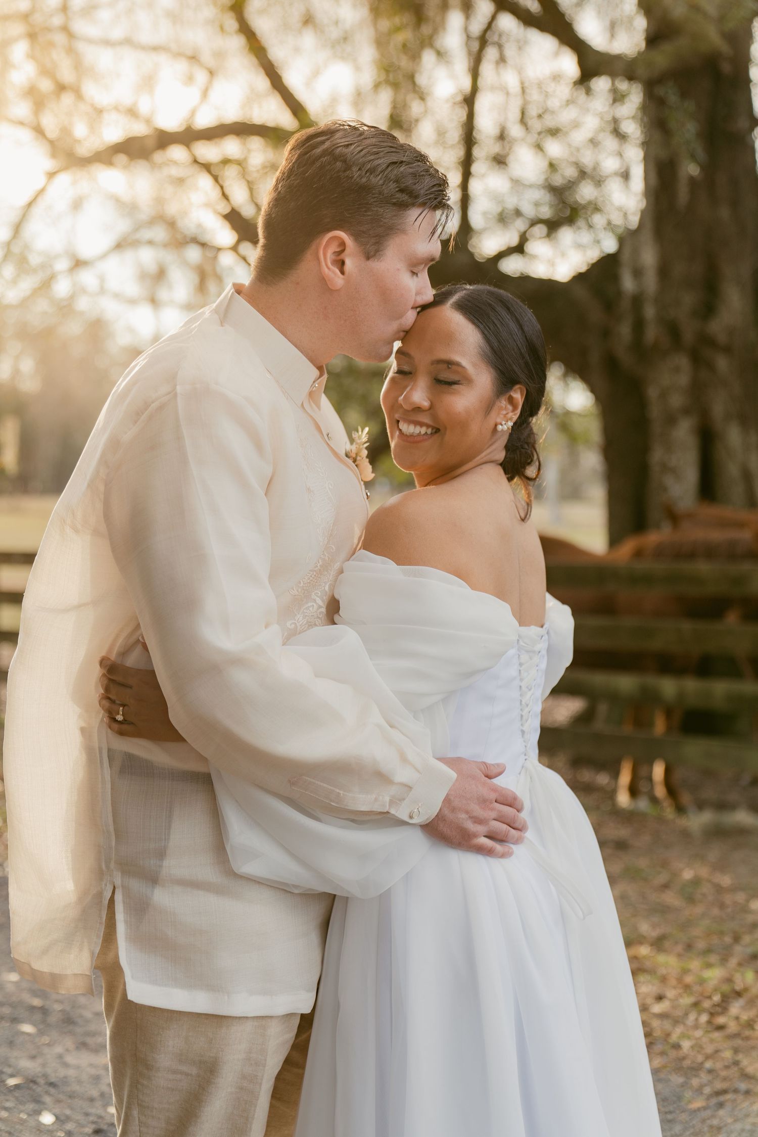 A couple shares an intimate moment in their wedding attire during golden hour in a garden setting.