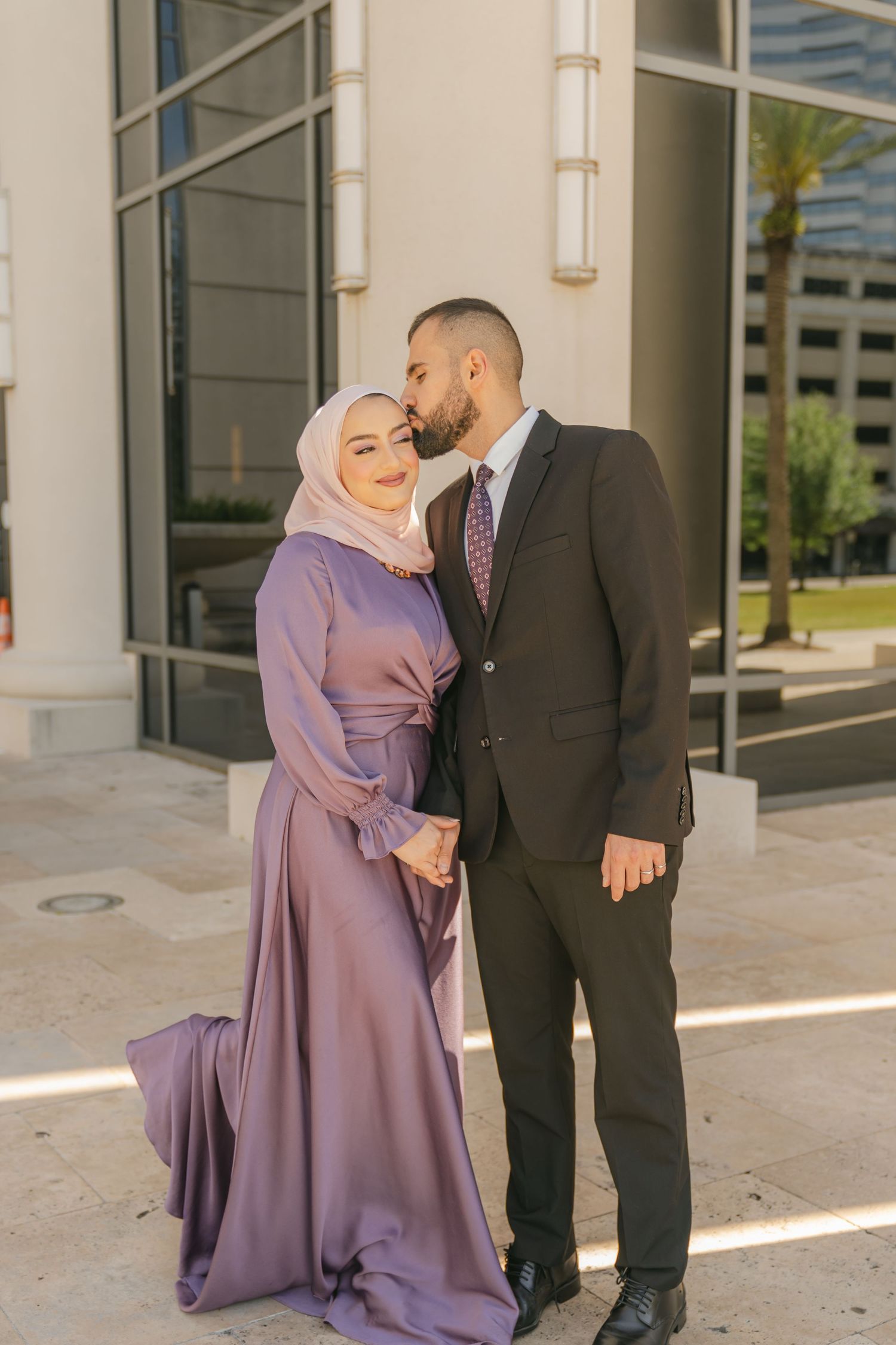 Elegant couple in formal wear sharing intimate moment outside building.