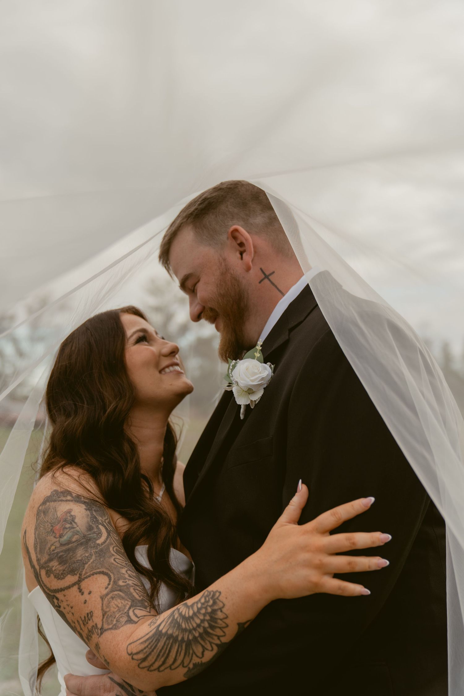 A romantic wedding photo series showing a couple sharing intimate moments under a flowing veil outdoors.