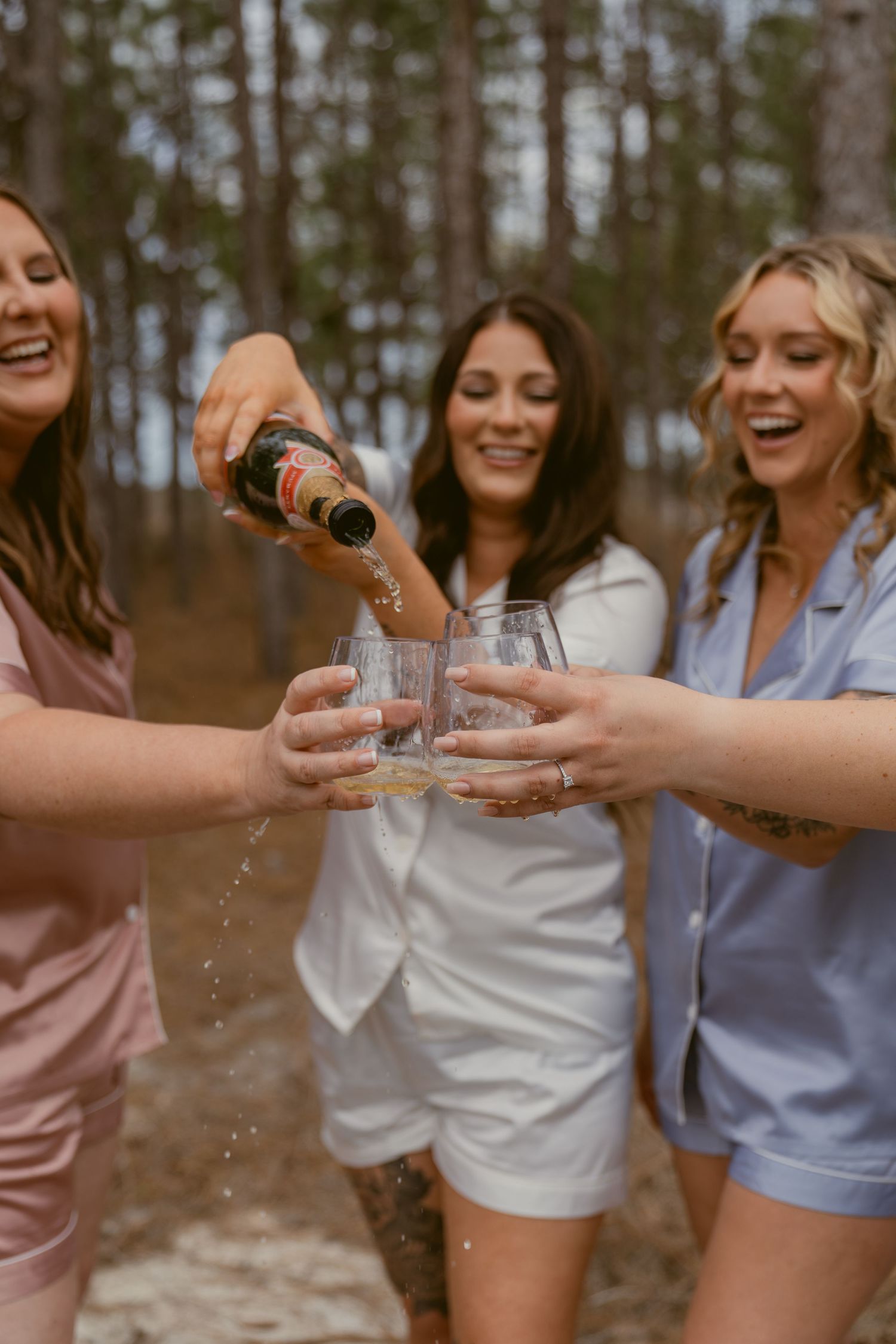 A group pours and shares champagne together in a celebratory moment outdoors.