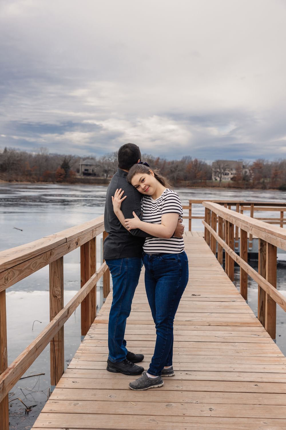 Romantic moment captured on wooden boardwalk overlooking winter lake landscape.