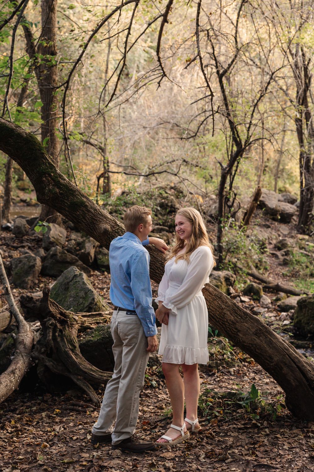 Couple sharing a romantic moment among fallen trees in an autumn forest setting.