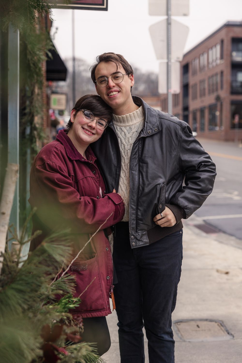 Urban streetscape engagement photoshoot with couple against brick buildings.