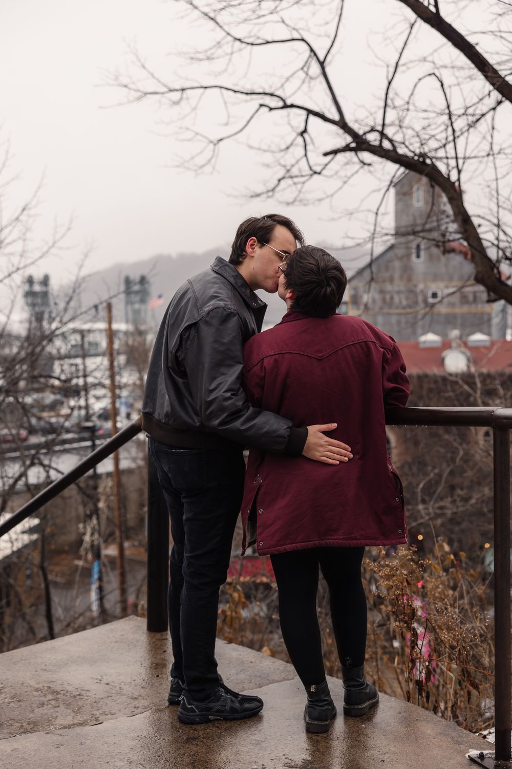 Romantic engagement photos captured on an overlook with city views in the background.