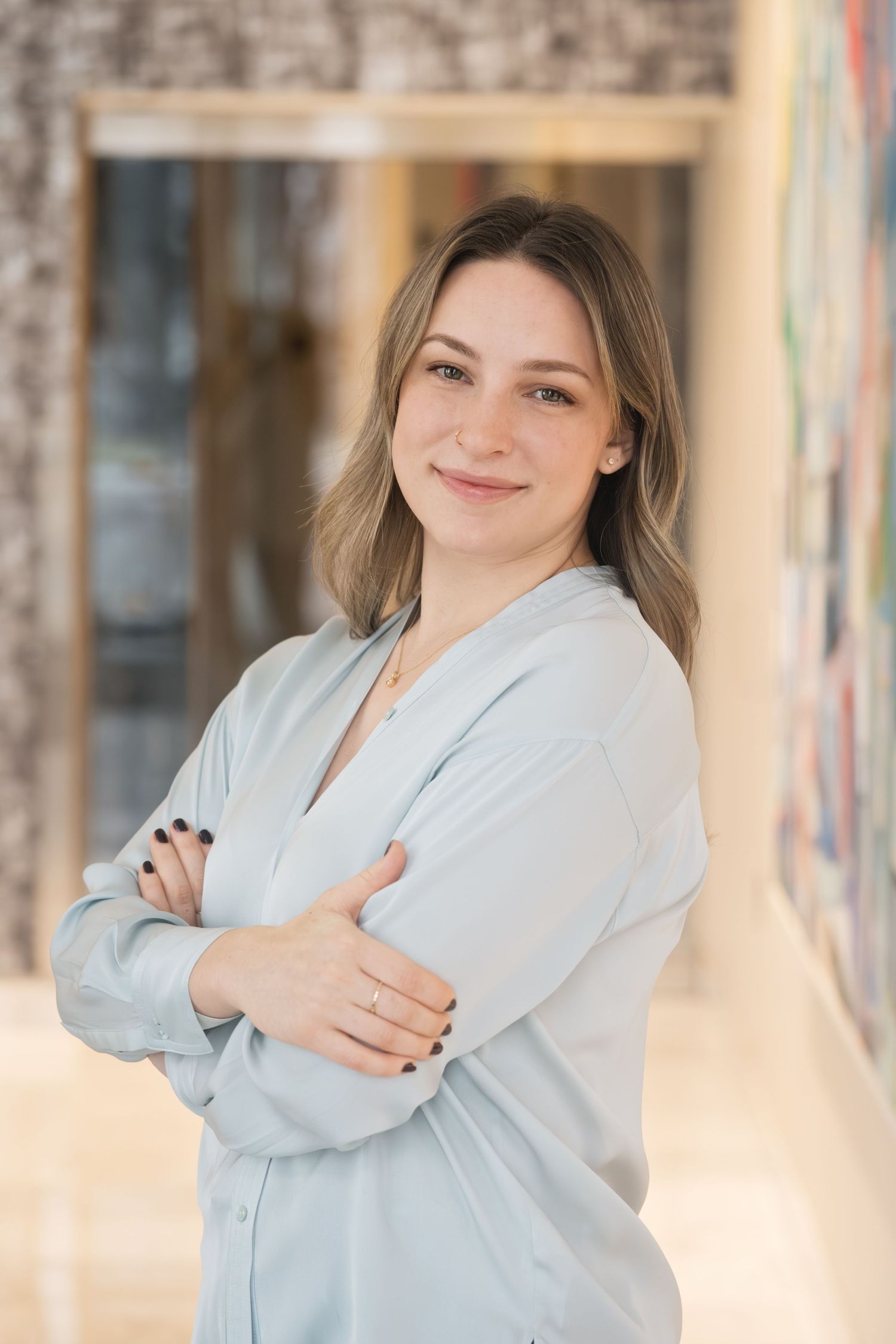 Close up portrait of a woman in blue blouse smiling with arms crossed - shot by Milwaukee headshot photographer Rachel Dickman.