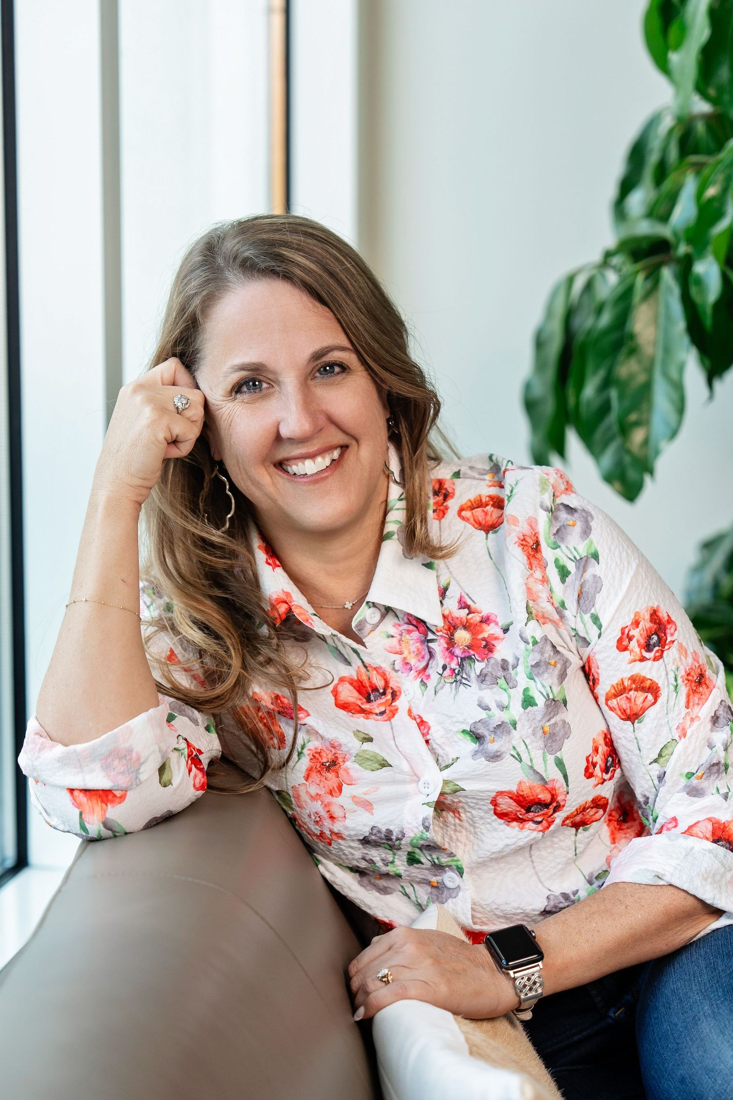 Branding photo by Milwaukee branding photographer Rachel Dickman of a woman sitting on a couch with a plant behind her.
