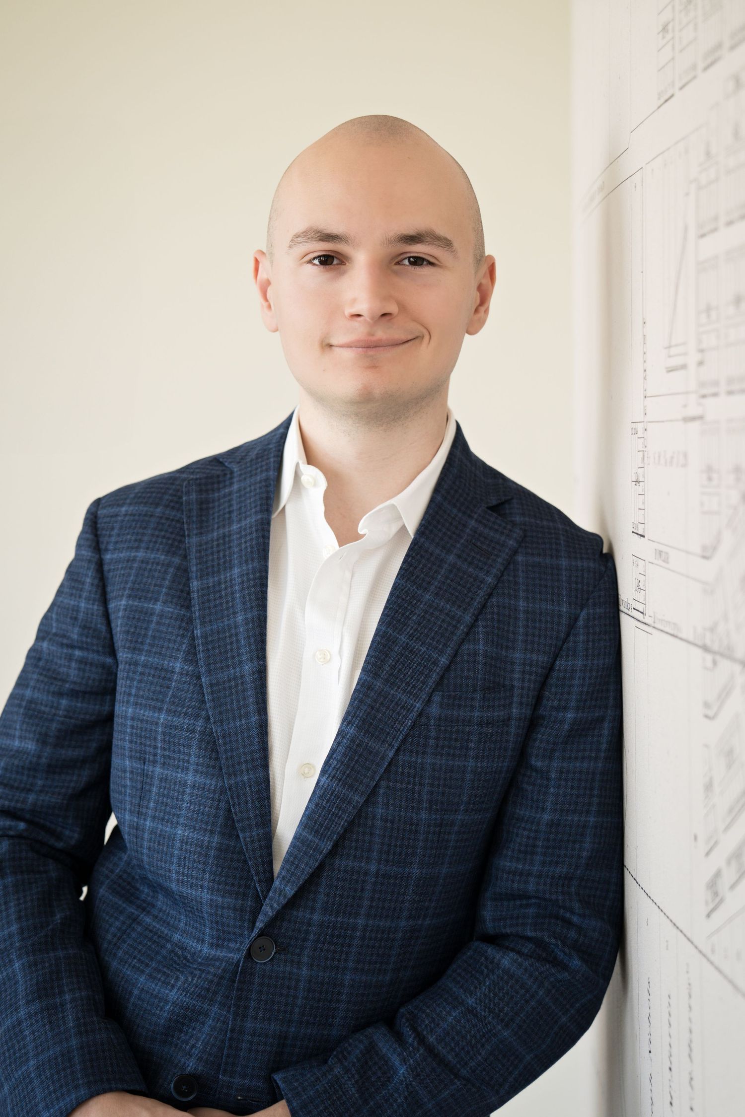 Professional portrait of man in suit leaning on white wall - shot by Milwaukee headshot photographer Rachel Dickman
