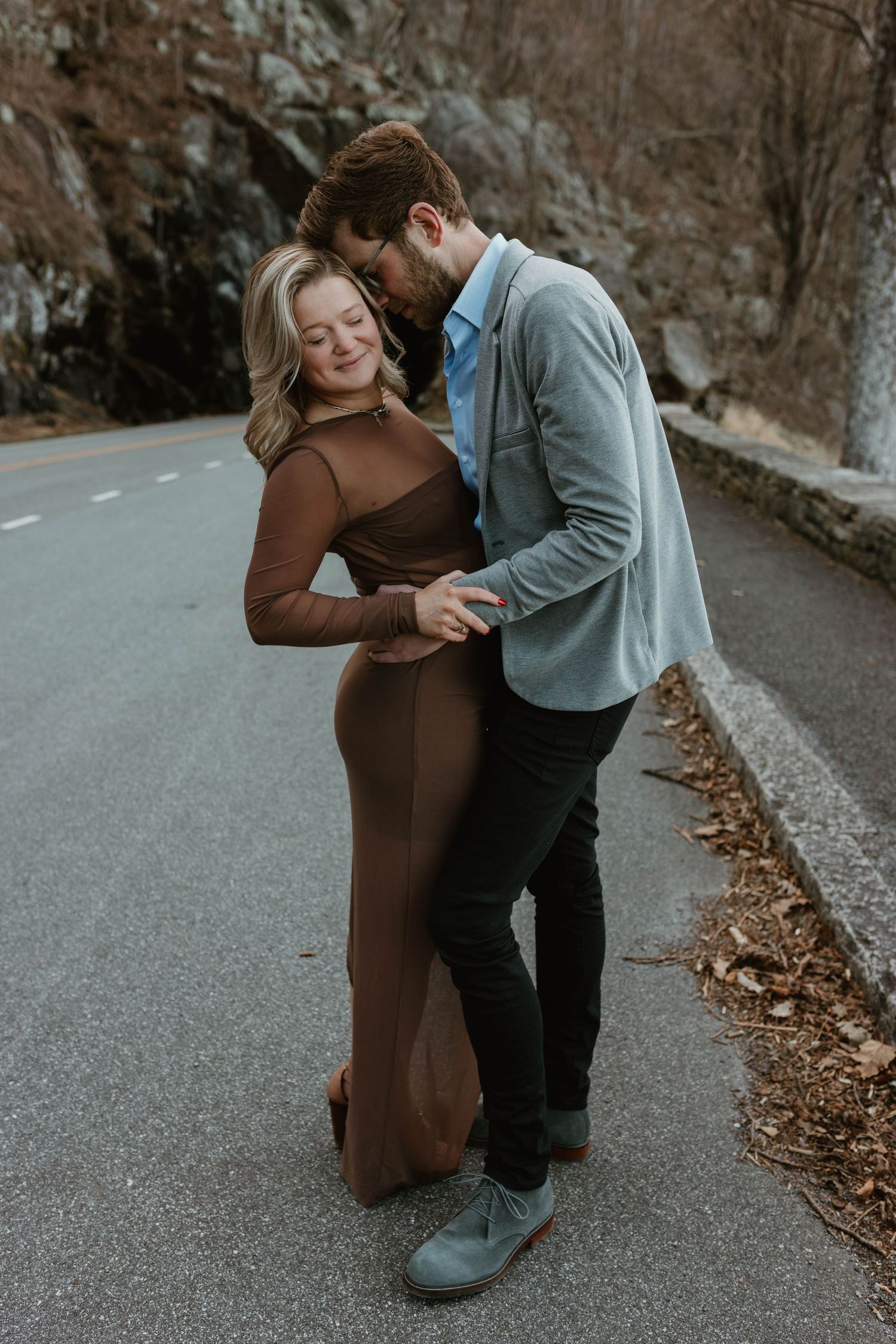 A couple shares playful moments on a winding autumn road.