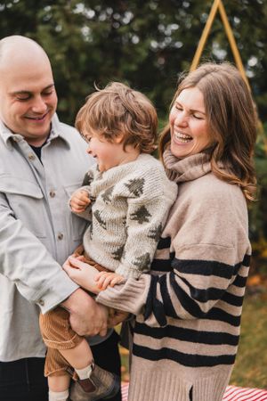 A family shares joyful moments together outdoors wearing cozy sweaters in autumn.