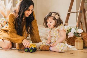 A series of candid lifestyle photos showing a parent and child playing together with toys and flowers at home.