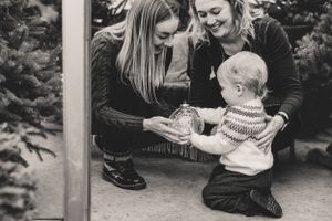A series of black and white photos showing tender moments between two parents and their child on greenhouse steps.