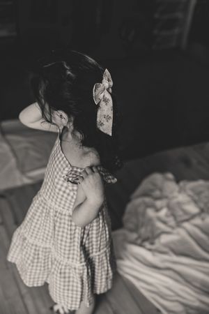 A sequence of black and white photos shows a small child in a gingham dress dancing around the room.