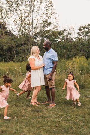 Family enjoying a candid moment together in a grassy meadow on a sunny summer day.