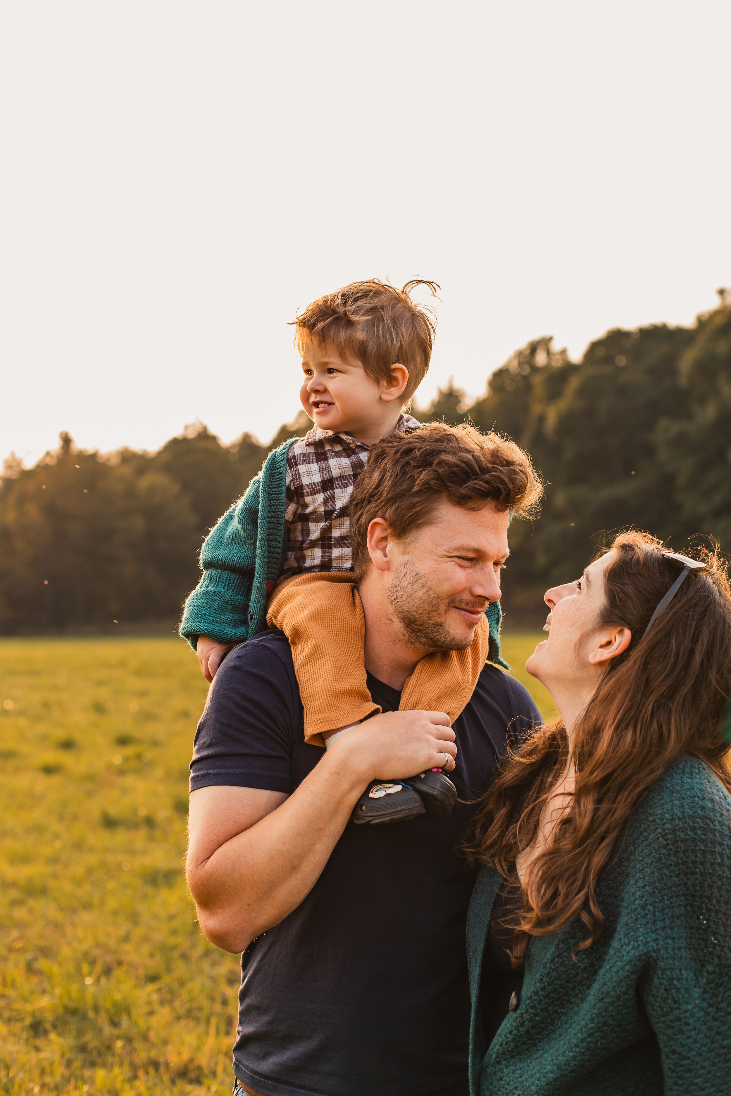 A happy family plays and laughs together in a golden sunlit field during sunset.