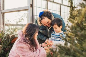 A family shares a tender moment together outdoors in a greenhouse before the holidays.