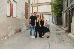 A family poses in an urban alleyway with brick walls and worn pavement in an artistic family photo.