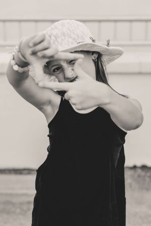 A person wearing a black sleeveless top gestures a film border with her hands in a fun, quirky and expressive photo.