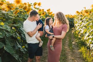 A family shares a joyful moment together in a sunflower field during golden hour.