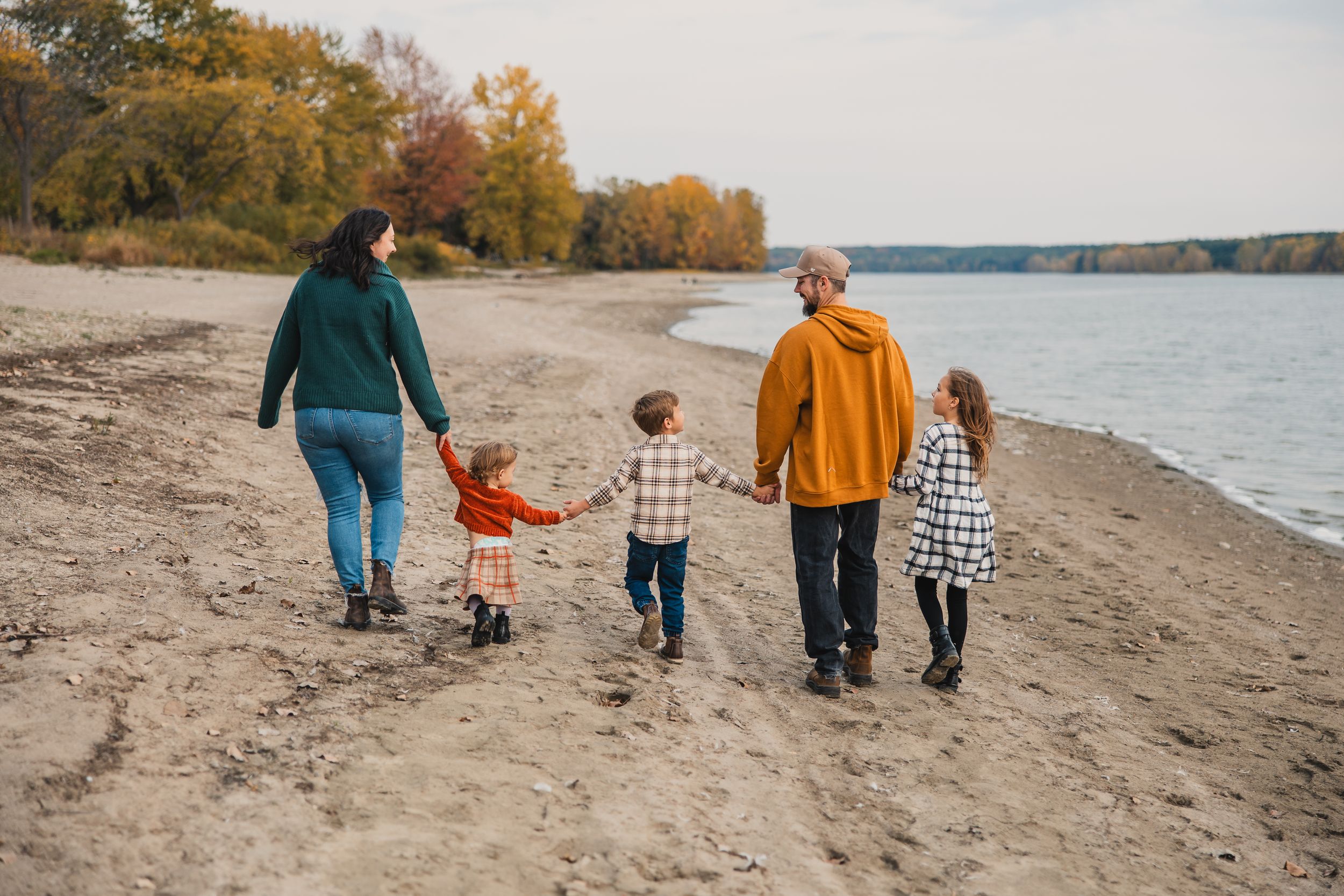 A family walks across the beach holding hands at sunset. Stratford, Ontario