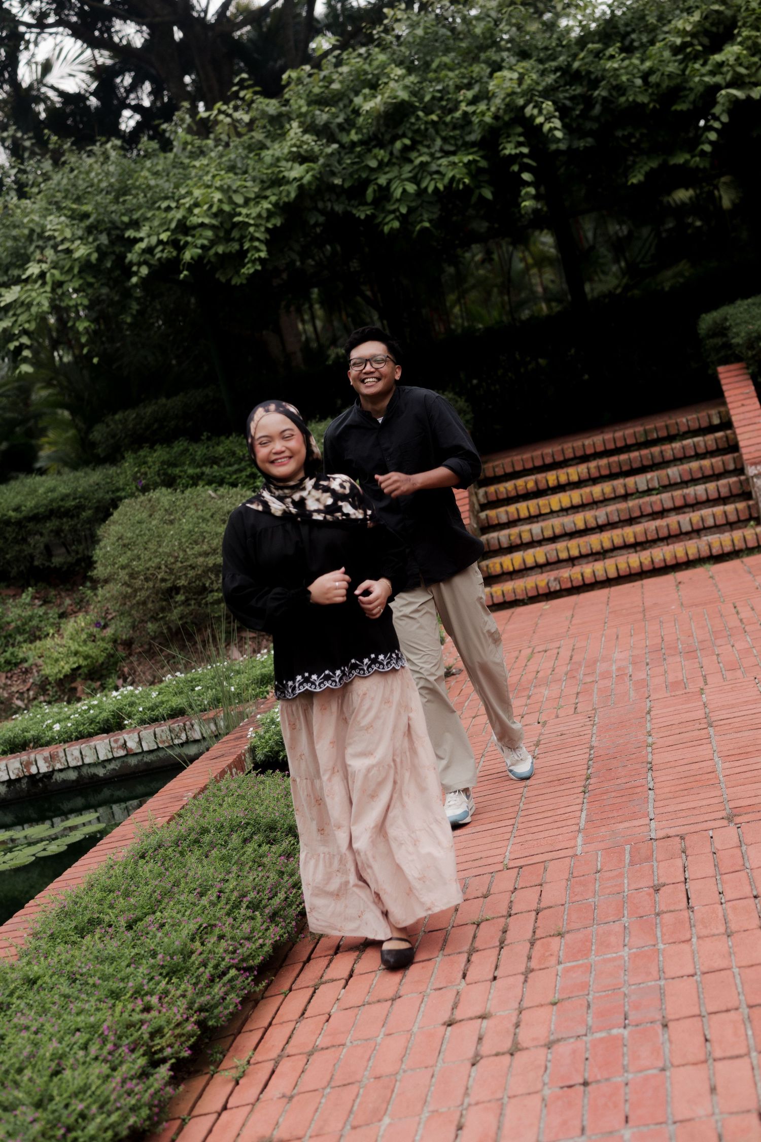 A couple poses together in front of a scenic waterfall backdrop during a photoshoot.