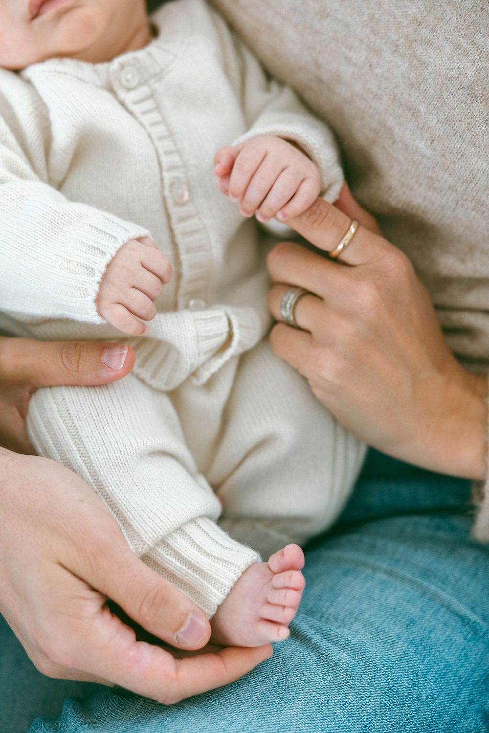 Close-up series of tiny baby feet being gently held by adult hands against white and blue textiles.