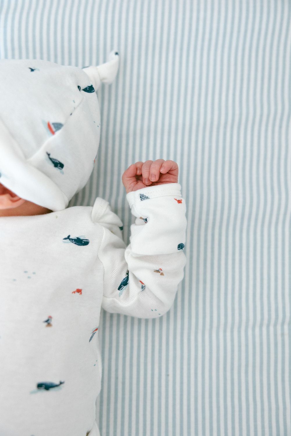 White fabric with delicate blue and coral pattern details on striped background.