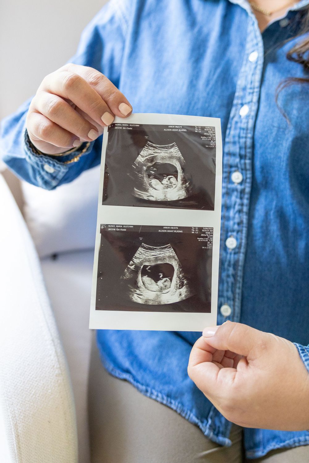 A woman in a denim shirt holds an ultrasound photo.