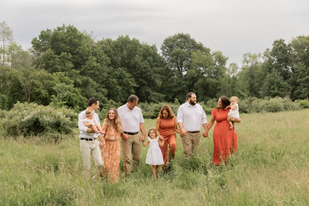 large family holding hands and walking together in a feild at Stoney Creek metropark
