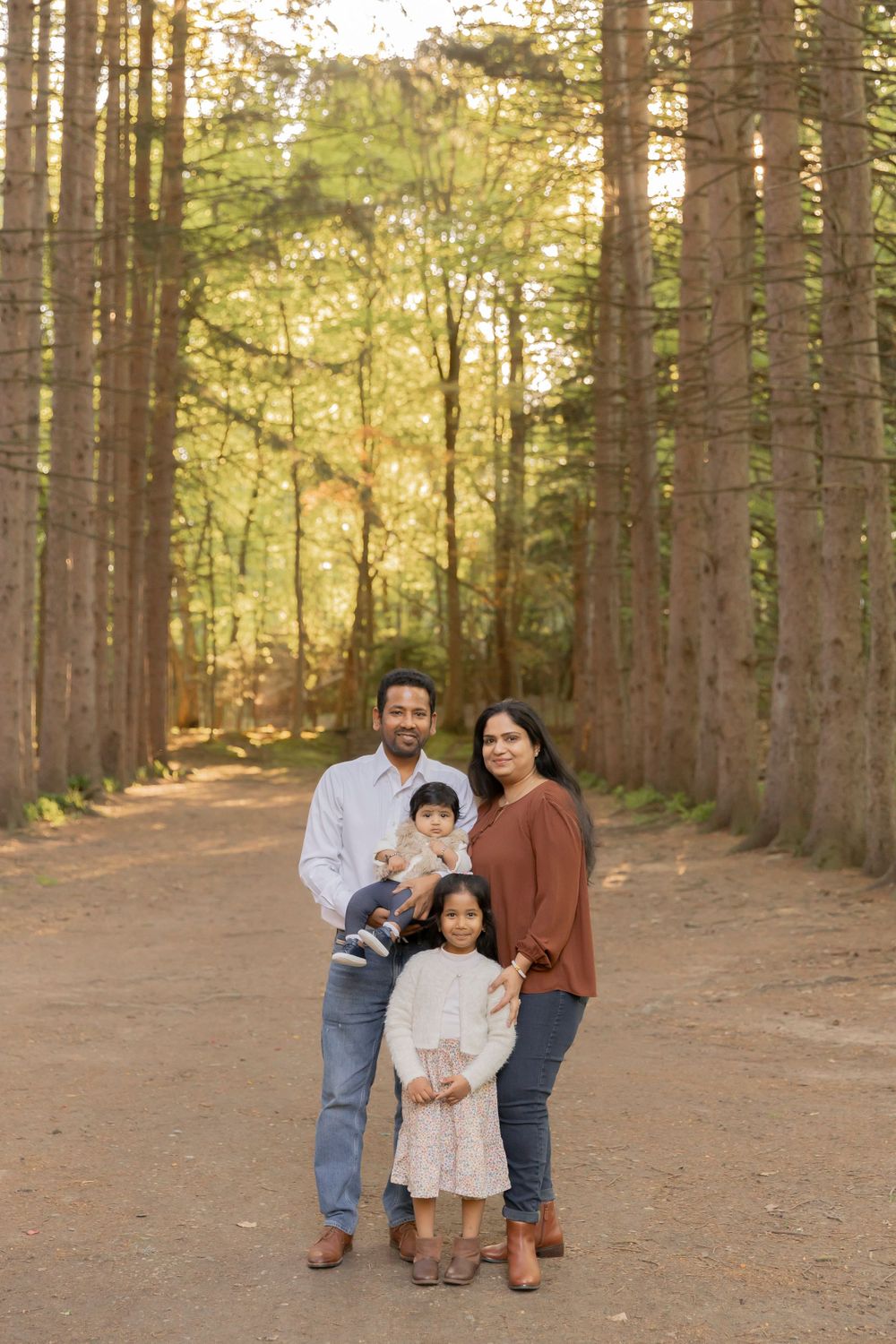 family posing for a photo in the evergreen trees at Sheldon estate