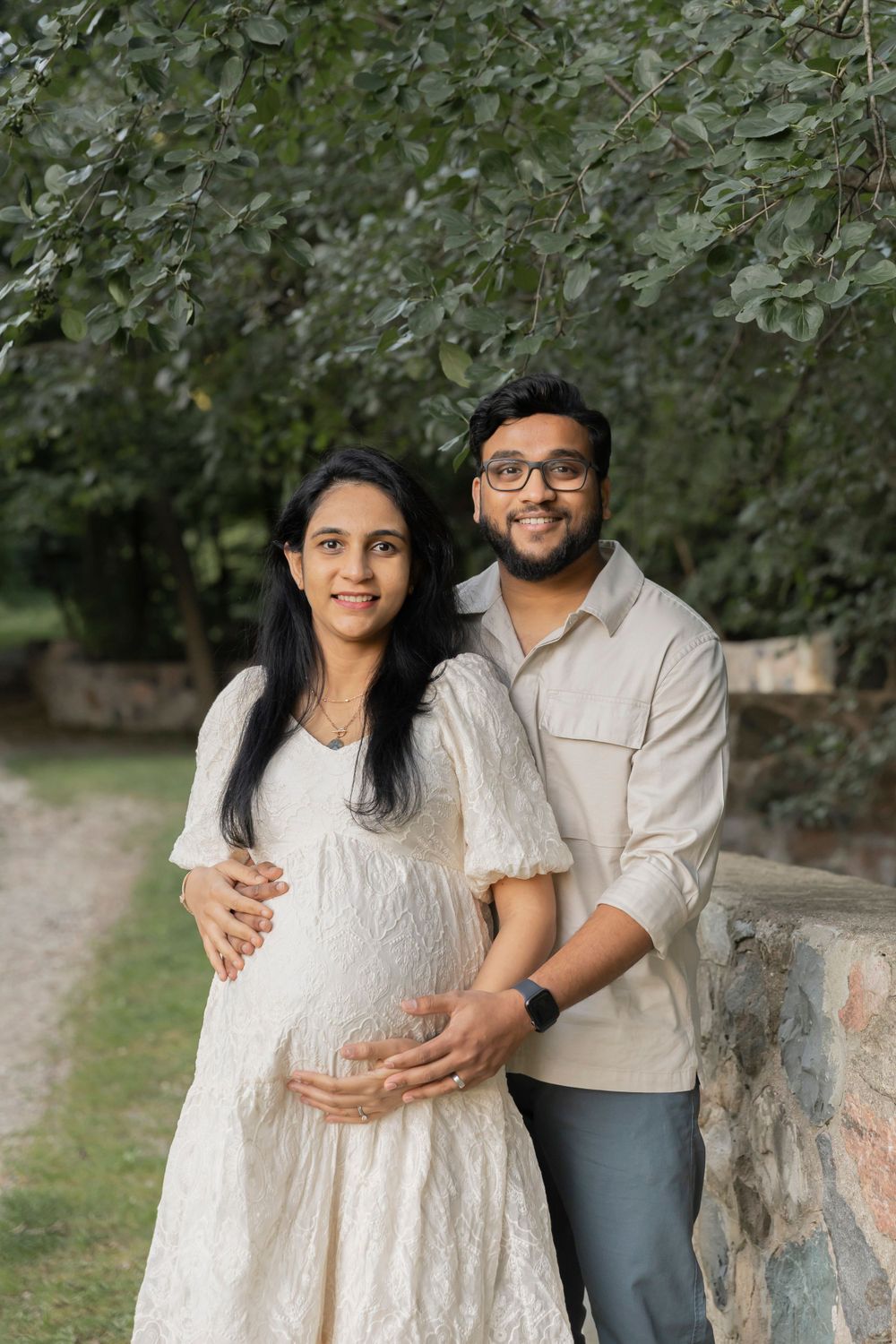pregnant couple holding wives belly and smiling for a photo at Sheldon estates
