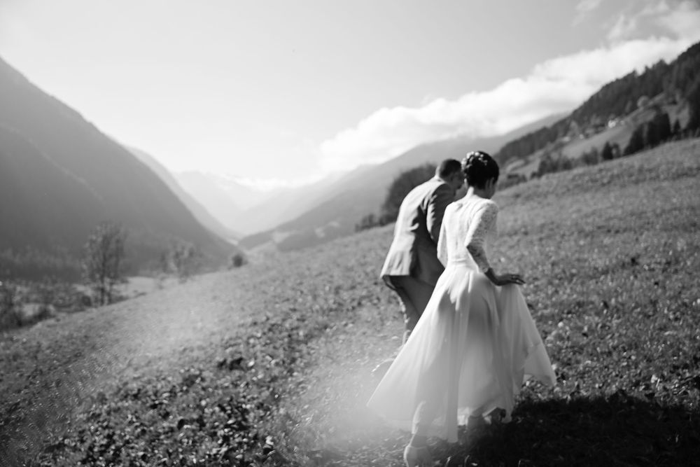 Schwarz-Weiß-Aufnahme des Brautpaares inmitten der weiten Tallandschaft des Stubaitals, Tirol