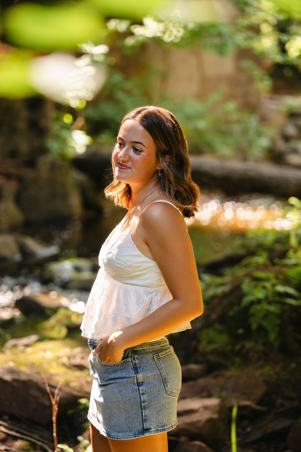 A summer outdoor photoshoot in a forest with natural sunlight filtering through trees creating a warm glowing effect.
