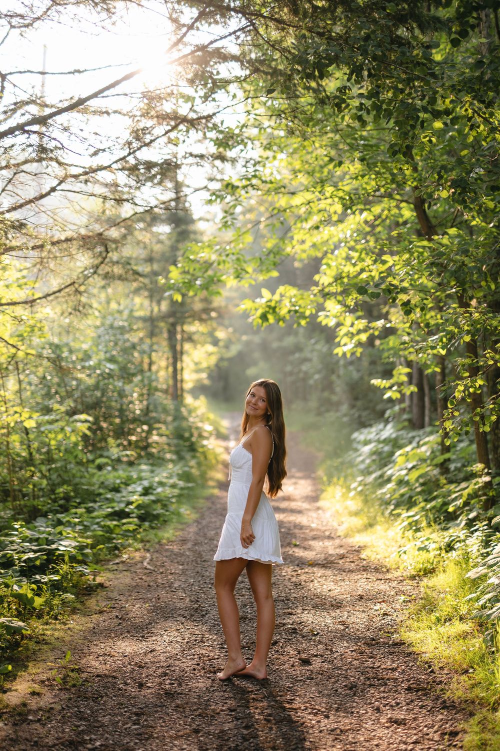 A dreamy forest path bathed in golden sunlight with a figure in white enjoying a peaceful morning walk.