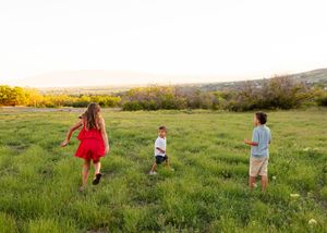 Family walking together through a green meadow at sunset.