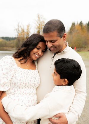 A family in white outfits shares an intimate moment together outdoors during autumn.