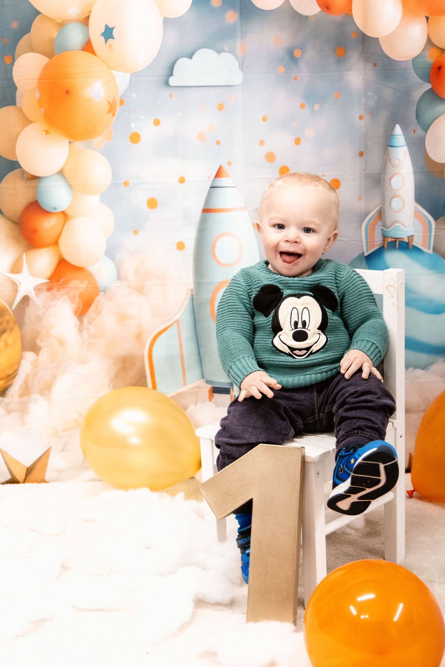 Space themed first birthday shoot with balloon arch and rocket ship decorations.
