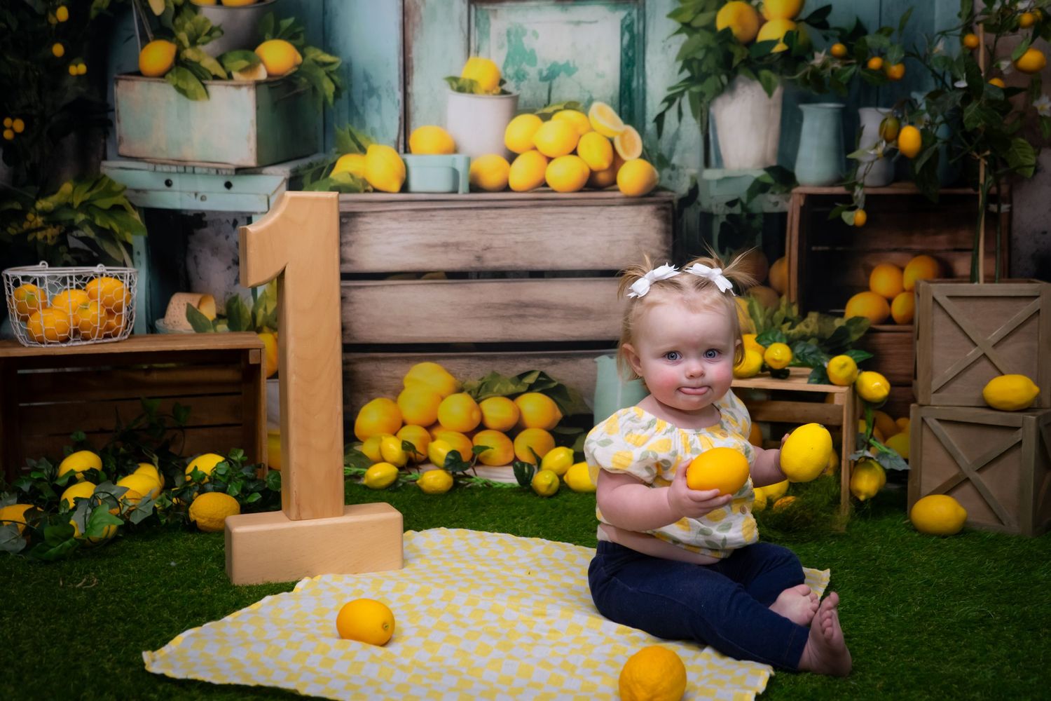 A child plays in a garden setting decorated with fresh yellow lemons and yellow gingham fabric accents.